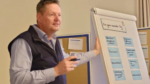 Berater erklärt das Flipchart „Ein ganz normaler Tag“ mit Karten zum Arbeitsablauf