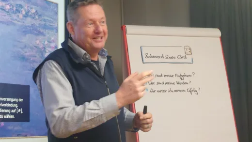 Martin Lange erklärt lachend ein Flipchart mit Leitfragen