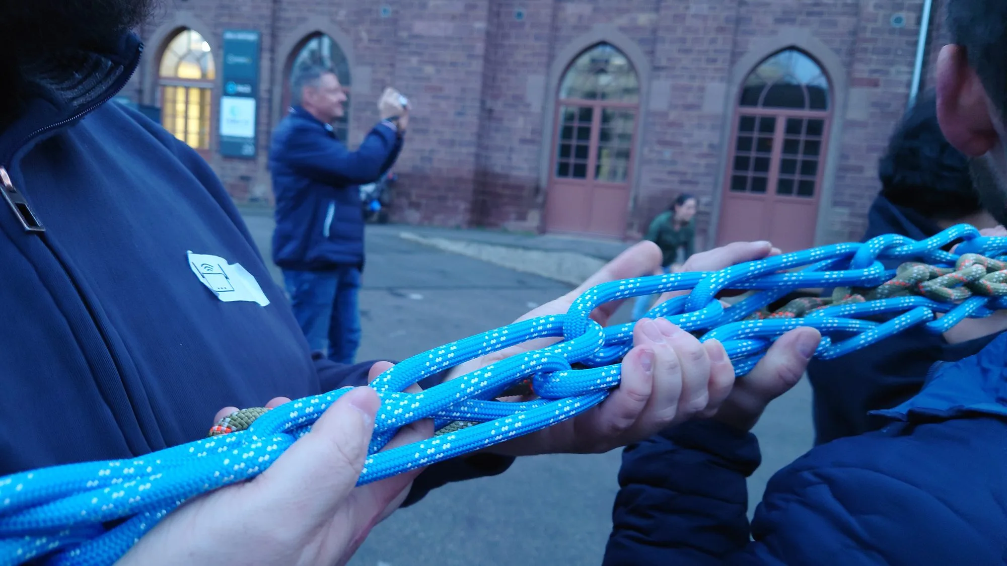 Hände halten ein blaues Seilgeflecht, Gruppe draußen